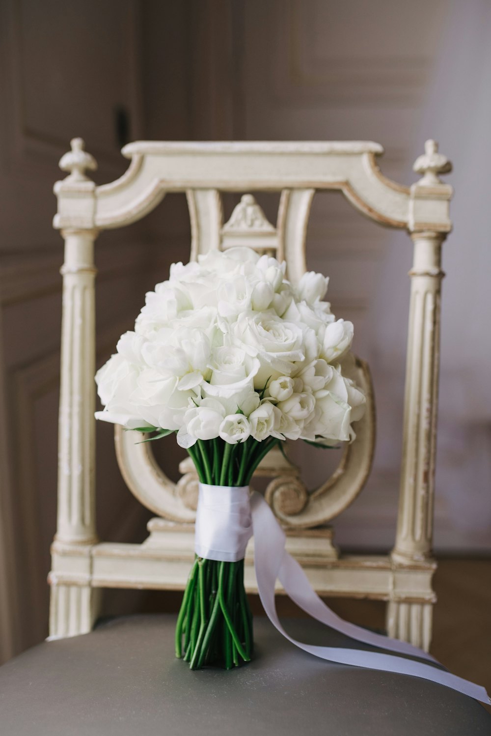 White bouquet resting on a carved chair