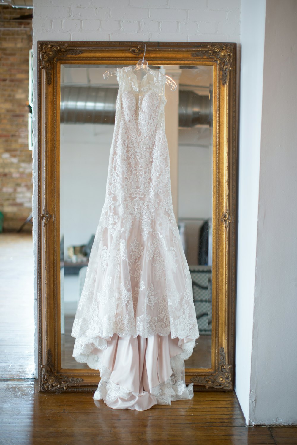 Lace gown in front of a gilt mirror