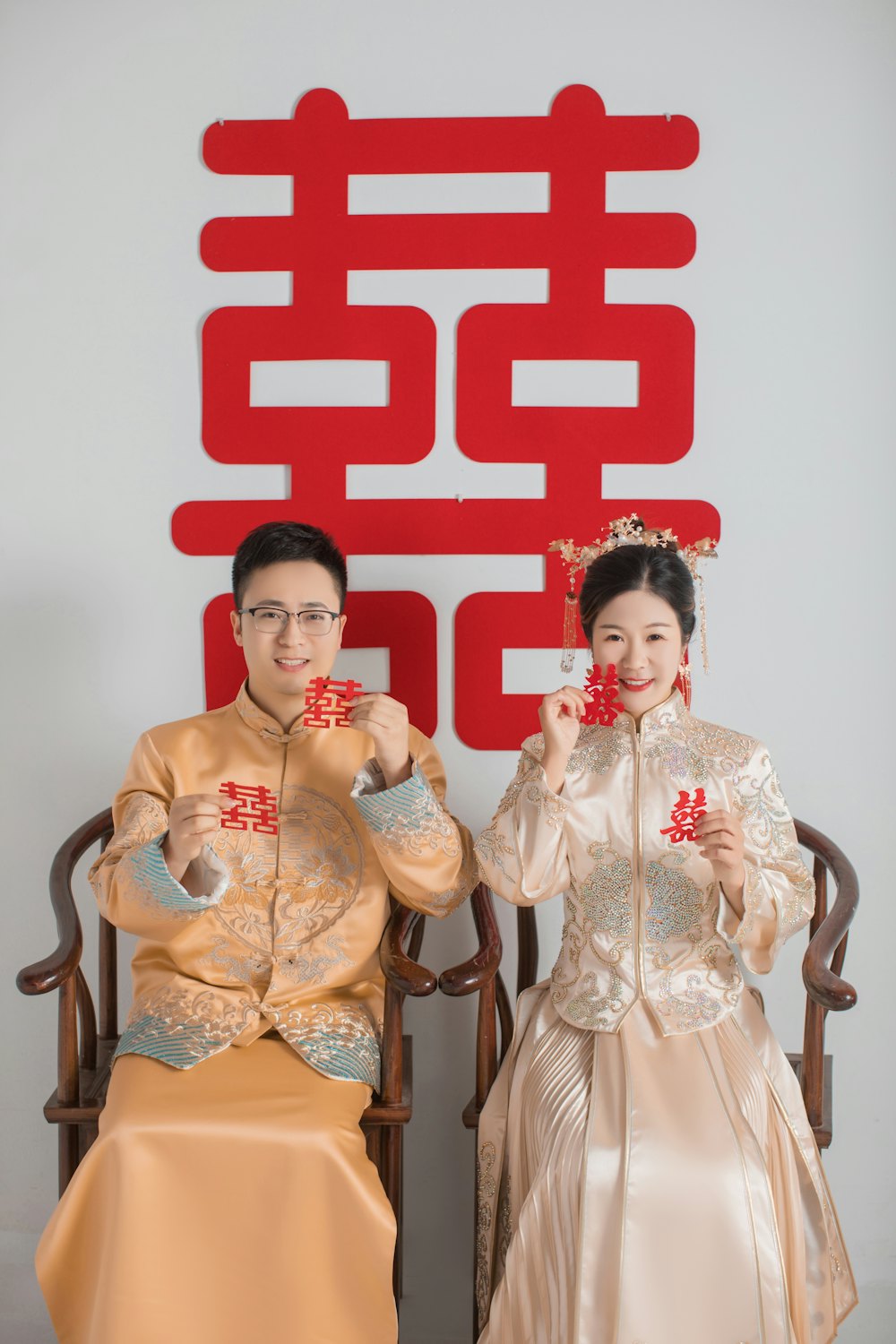 Couple in traditional dress holding double happiness cards