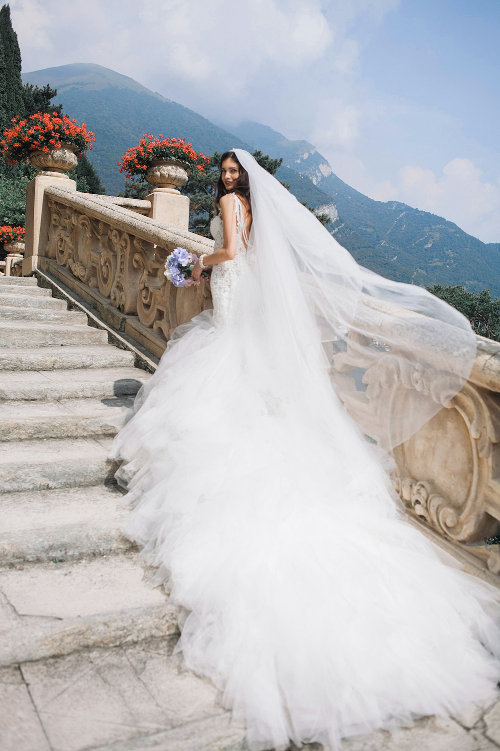 Bride with a long veil on stone stairs