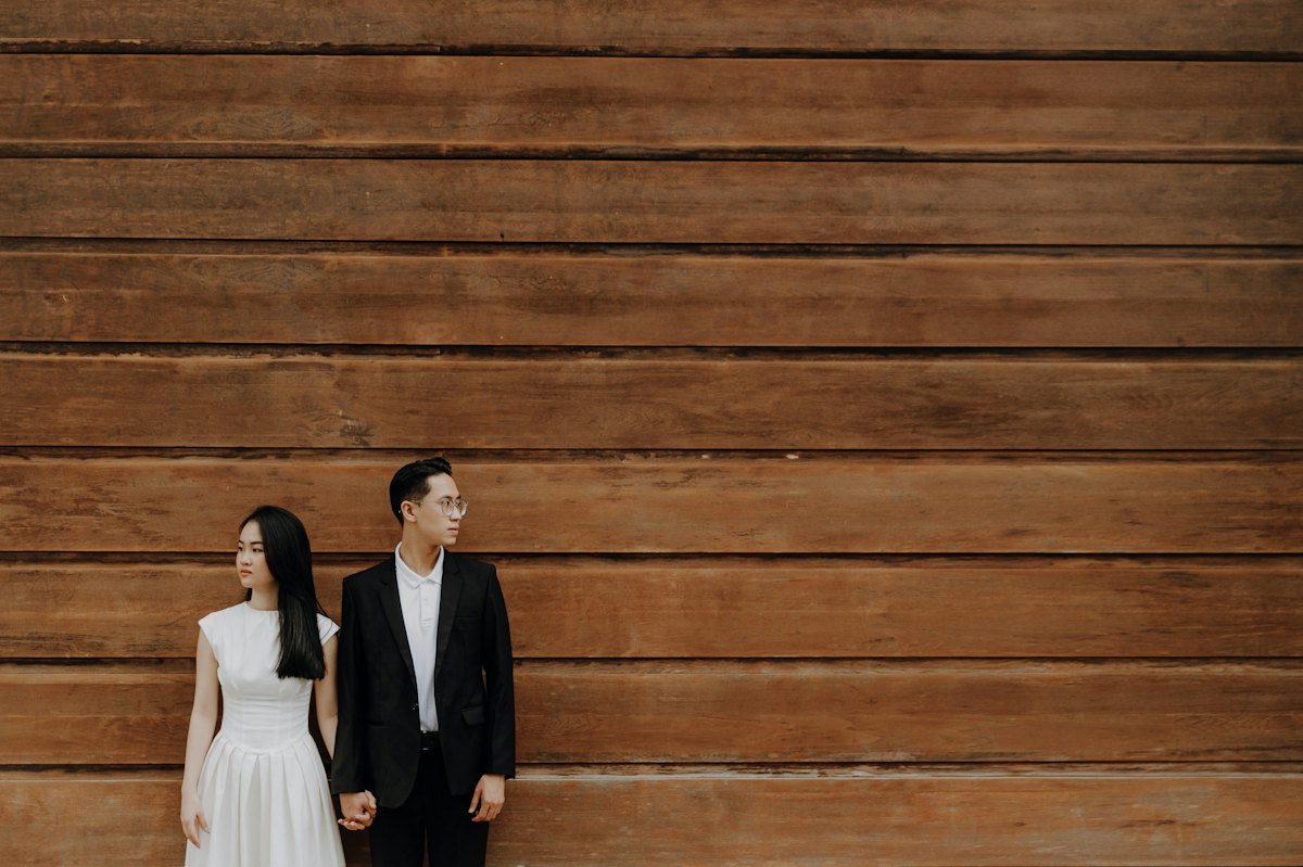 Couple standing against a dark timber wall