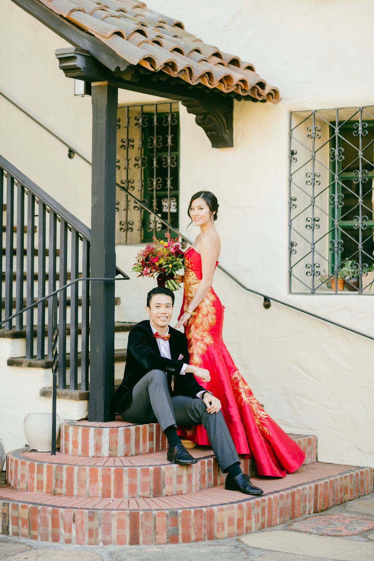 Couple sitting on red brick steps in a red qipao and dark suit