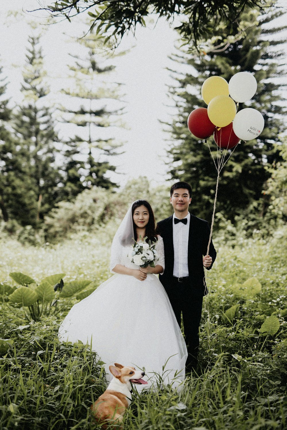 Couple with balloons and their dog in a garden