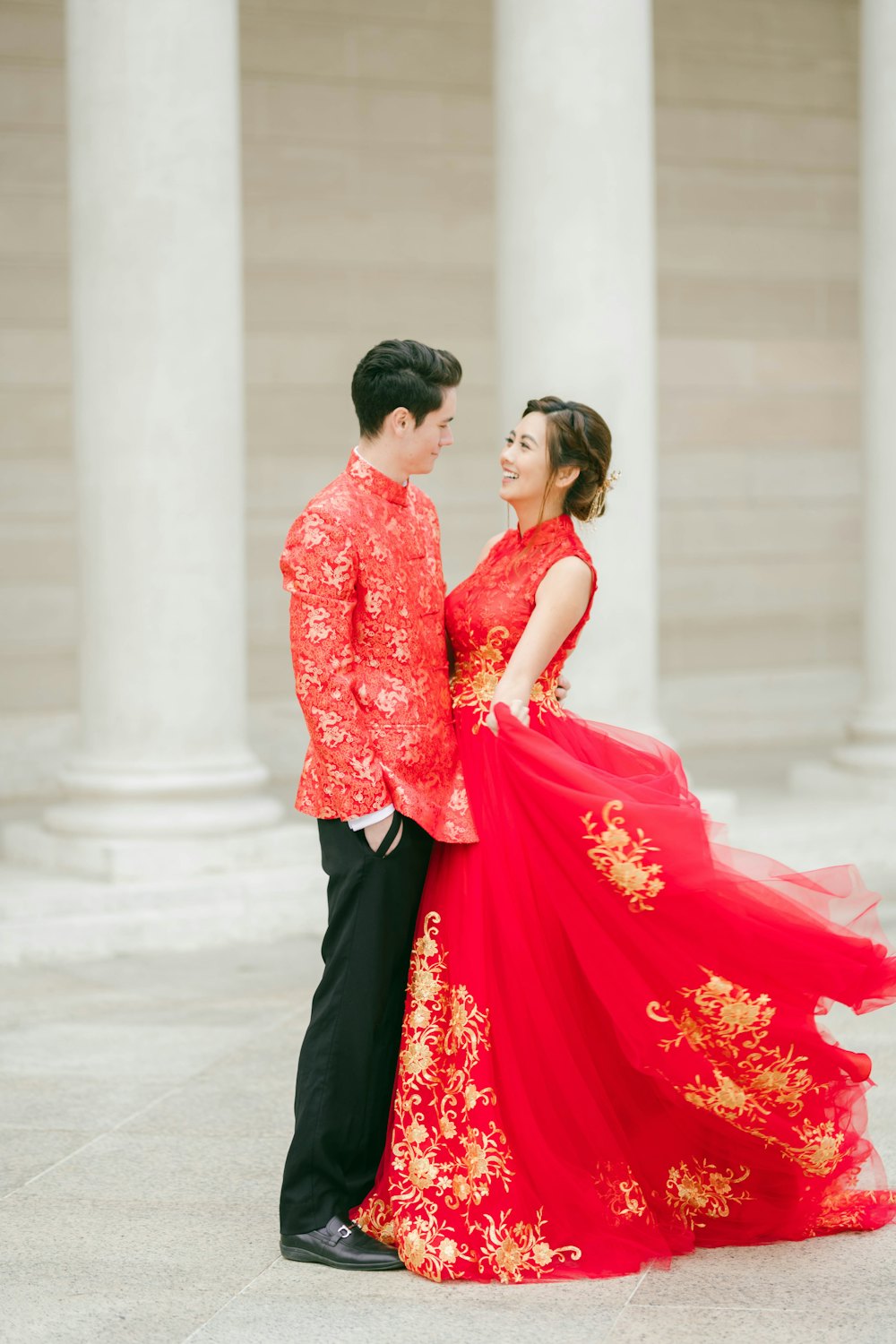Couple in a red embroidered gown beside white columns